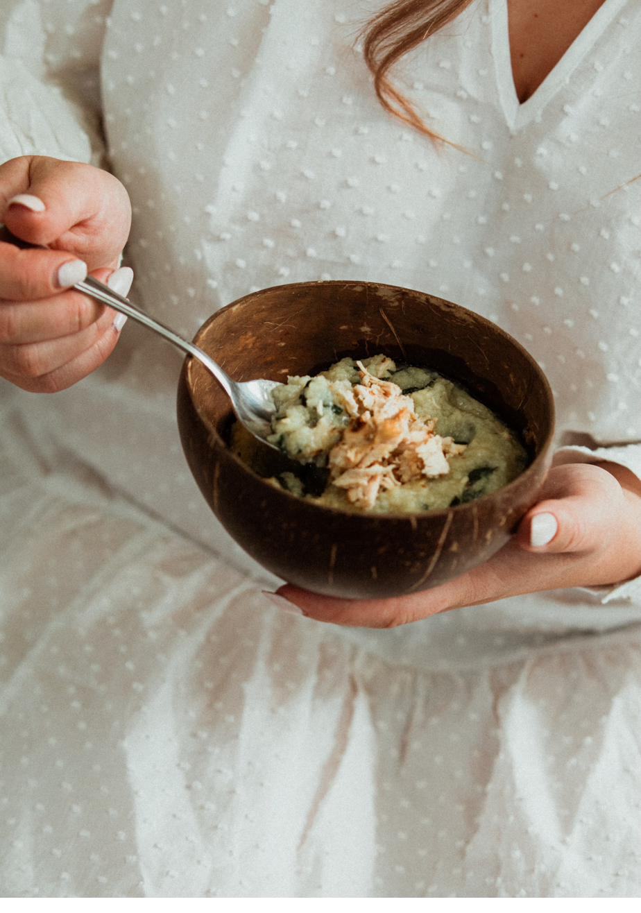 A mother eating a bowl of chicken and greens
